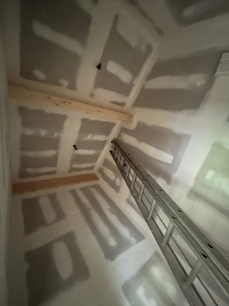 Plaques et joints au plafond et sur les murs, avec une échelle d’accès.